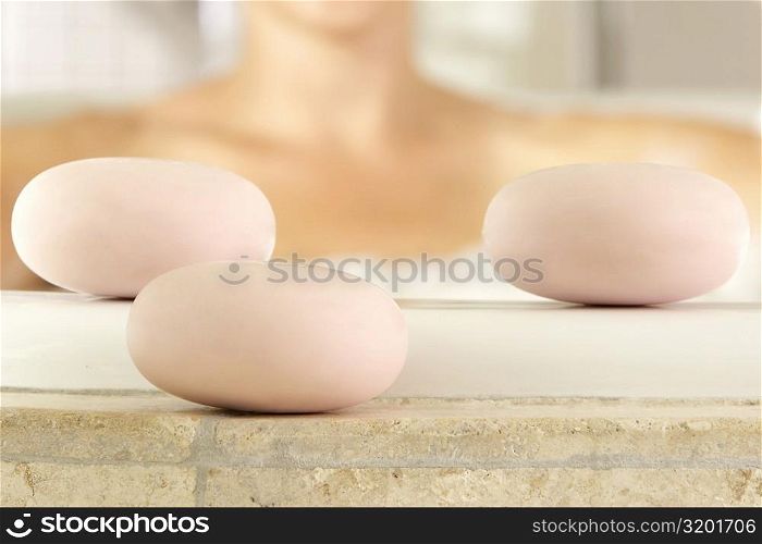 Close-up of three soaps at the edge of a bathtub