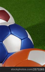 Close-up of three soccer balls on the grass