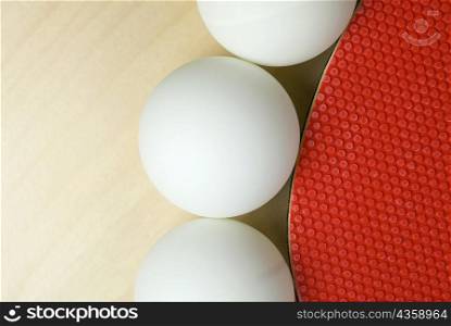 Close-up of three table tennis balls with a table tennis racket
