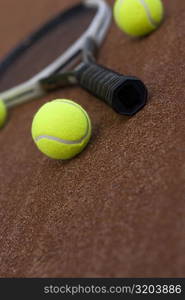 Close-up of three tennis balls and a racket in a court