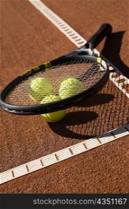 Close-up of three tennis balls and a racket in a court