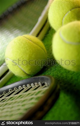 Close-up of three tennis balls and two tennis rackets