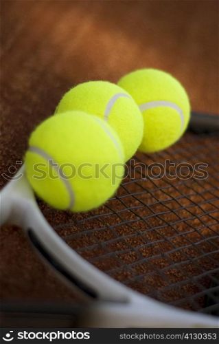 Close-up of three tennis balls on a tennis racket