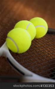 Close-up of three tennis balls on a tennis racket