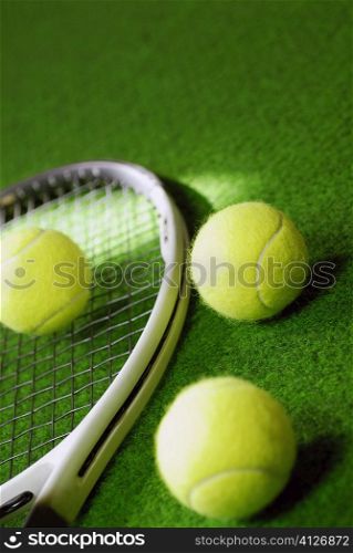 Close-up of three tennis bowls and a tennis racket