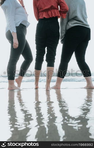 Close up of three women legs on the beach during a sunny day, vacation and relax concept