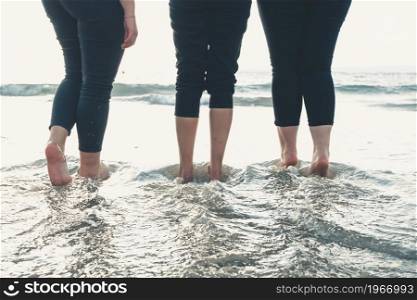 Close up of three women legs on the beach during a sunny day, vacation and relax concept