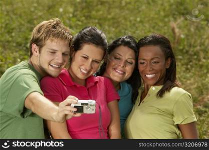 Close-up of three young women and a young man photographing themselves