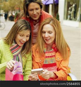 Close-up of three young women looking at a digital camera and smiling