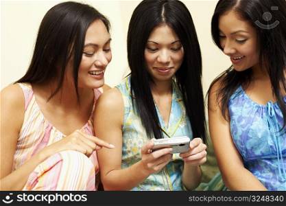 Close-up of three young women looking at a digital camera and smiling