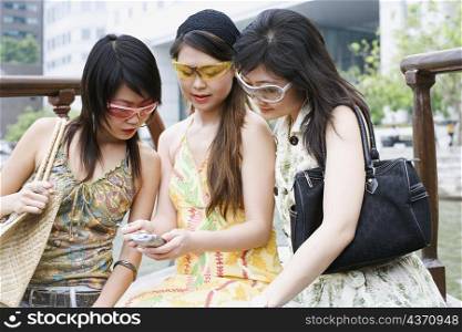 Close-up of three young women looking at a mobile phone