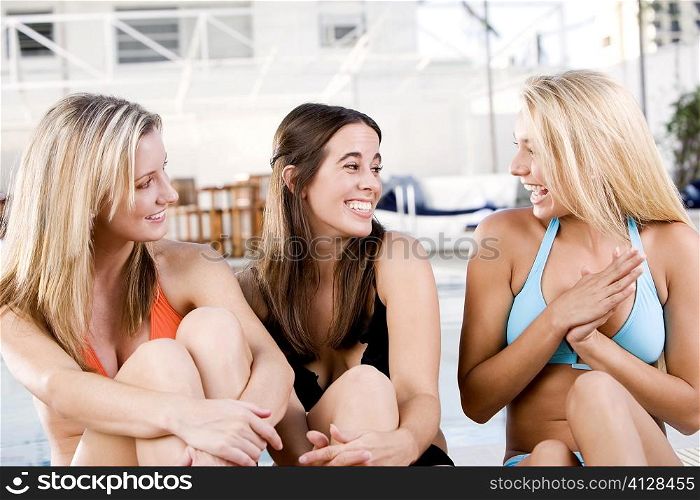 Close-up of three young women sitting at the poolside