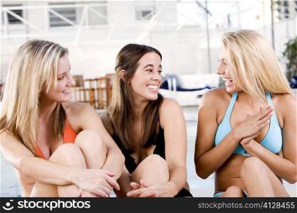 Close-up of three young women sitting at the poolside