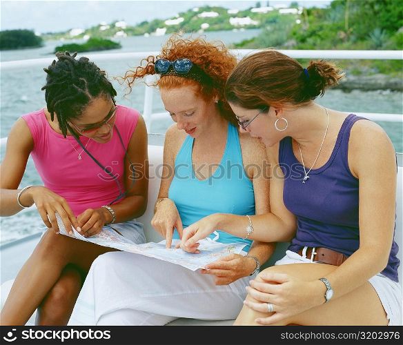 Close-up of three young women sitting on a bench and looking at a map, Bermuda