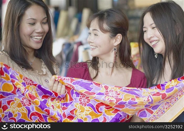 Close-up of three young women smiling in a clothing store
