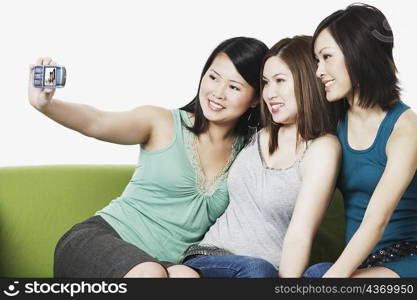 Close-up of three young women taking a photograph of themselves with a mobile phone camera