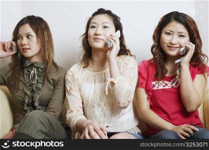 Close-up of three young women talking on mobile phones