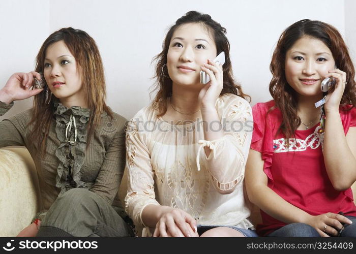 Close-up of three young women talking on mobile phones