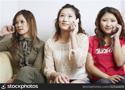 Close-up of three young women talking on mobile phones