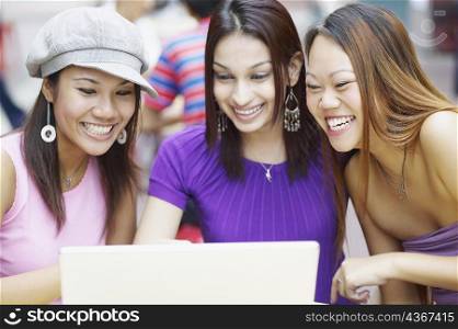 Close-up of three young women using a laptop