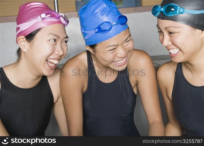 Close-up of three young women wearing swimwear and smiling