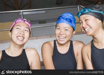 Close-up of three young women wearing swimwear and smiling