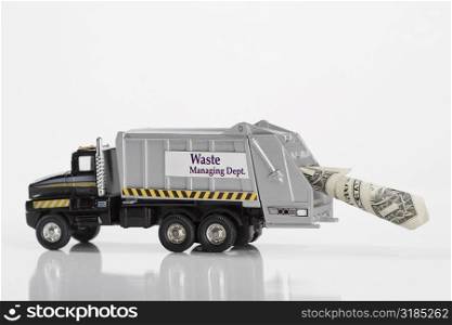 Close-up of toy garbage truck carrying US dollar bill