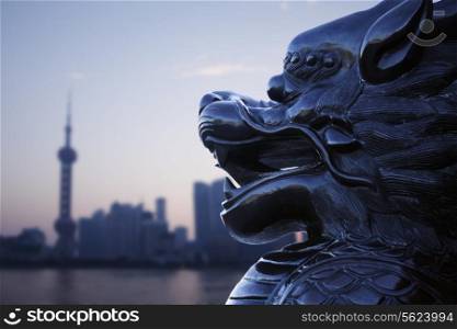 Close-up of traditional Chinese statue with Shanghai skyline in the background