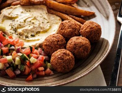 Close-up of Traditional falafel balls with salad and hummus on a plate.