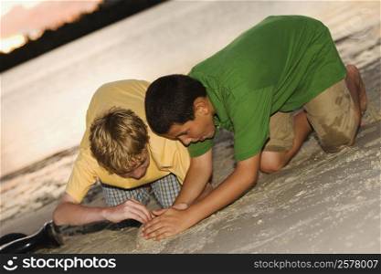 Close-up of two boys making a sand castle