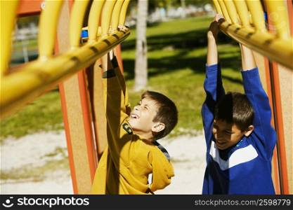 Close-up of two brothers hanging on a jungle gym