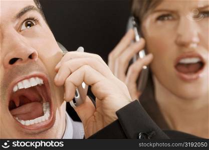 Close-up of two business executives shouting on mobile phones