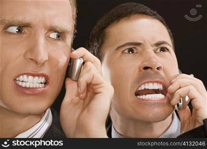 Close-up of two business executives shouting on mobile phones