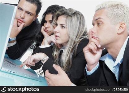 Close-up of two businessmen and two businesswomen in front of a laptop and thinking