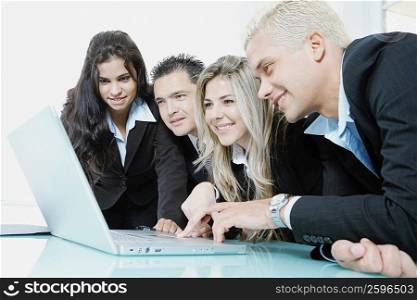Close-up of two businessmen and two businesswomen using a laptop