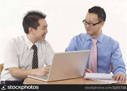 Close-up of two businessmen sitting in front of a laptop