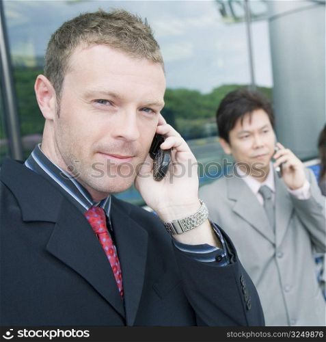 Close-up of two businessmen talking on mobile phones
