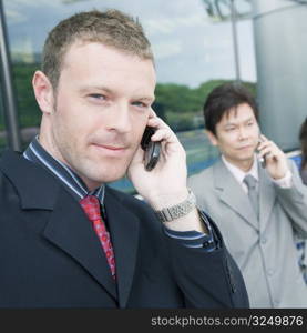 Close-up of two businessmen talking on mobile phones