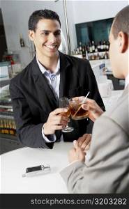 Close-up of two businessmen toasting with drinks in a bar