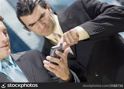 Close-up of two businessmen using a palmtop