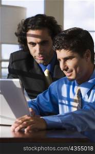Close-up of two businessmen working on a laptop