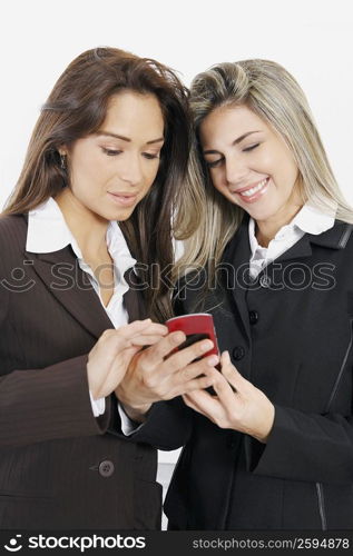 Close-up of two businesswomen holding a mobile phone and smiling