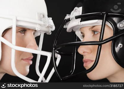 Close-up of two businesswomen wearing football helmets and looking at each other