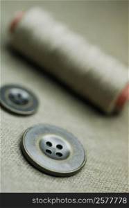 Close-up of two buttons with a spool of thread