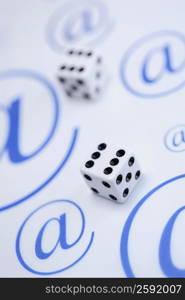 Close-up of two dices on a sheet of paper with At symbols