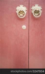 Close-up of two doorknockers with a keyhole on a door