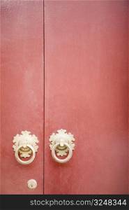Close-up of two doorknockers with a keyhole on a door