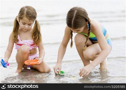 Close-up of two girls playing with toys on the beach