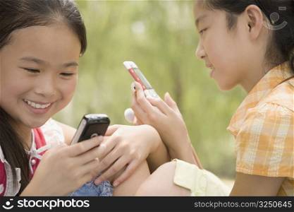 Close-up of two girls using their mobile phones