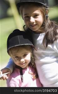Close-up of two girls wearing riding hats and smiling